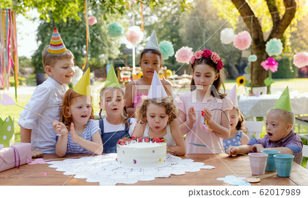 Down syndrome child with friends on birthday party outdoors in garden. 62017989