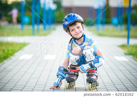 Smiling boy with inline skates and protective gear Smiling boy with inline skates and protective gear 62018162