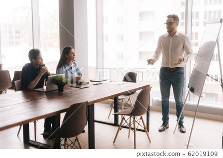Businessman doing presentation, using whiteboard, explaining to colleagues 62019109