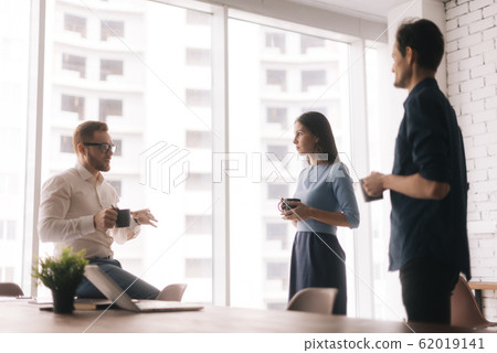 Smiling young colleagues talking at coffee break. Smiling young colleagues talking at coffee break. 62019141