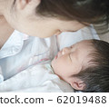 Closeup a baby sleeping comfortably in in the mother's arms 62019488