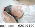 Closeup a baby sleeping comfortably in the mother's arms 62019490