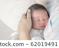 Closeup a baby sleeping comfortably in in the mother's arms 62019491