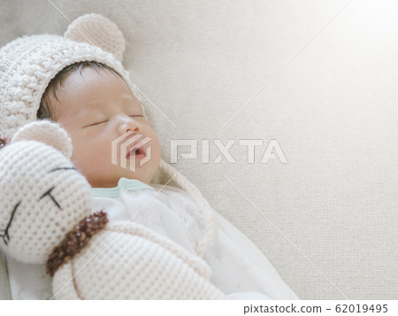 Closeup a baby sleeping comfortably on sofa with bear doll 62019495
