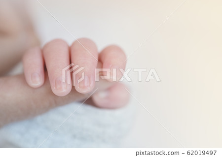 Closeup baby hand is holding the mother's finger with copy space Closeup baby hand is holding the mother's finger with copy space 62019497