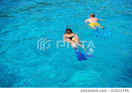 Woman and man dive with flippers and mask in turquoise waters of Aegean Sea, Greece. 62022346