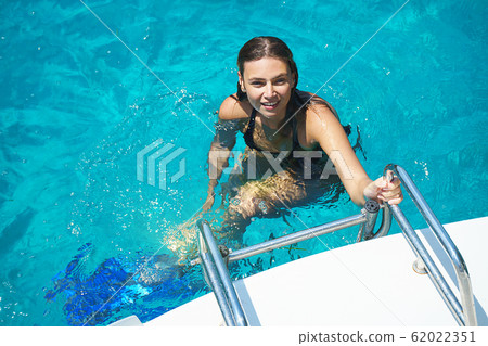 Happy beautiful woman is swimming in turquoise sea on summer holidays. Happy beautiful woman is swimming in turquoise sea on summer holidays. 62022351