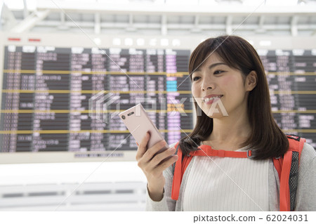 Airport lobby bulletin board woman mobile phone 62024031