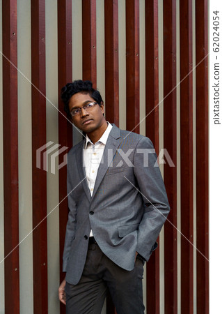 Handsome young mixed race man looking over his glasses.  62024054