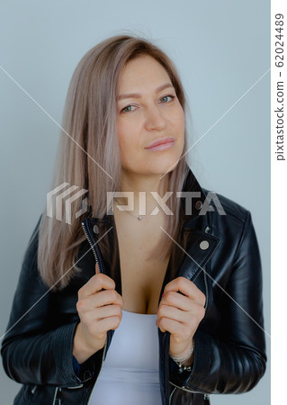 Blondie woman in a black leather jacket is in the minimalistic apartment. Blondie woman in a black leather jacket is in the minimalistic apartment. 62024489