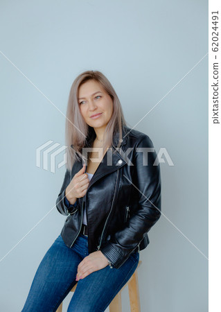 Blondie woman in a black leather jacket is in the minimalistic apartment. Blondie woman in a black leather jacket is in the minimalistic apartment. 62024491