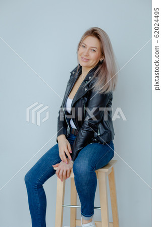 Blondie woman in a black leather jacket is in the minimalistic apartment. Blondie woman in a black leather jacket is in the minimalistic apartment. 62024495