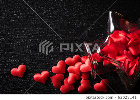 Red hearts from glass bottle on black background. Red hearts from glass bottle on black background. 62025141