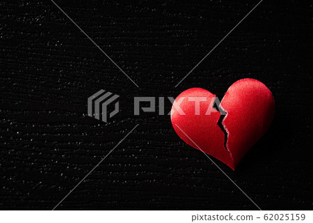 Broken red heart on black wooden background. Broken red heart on black wooden background. 62025159