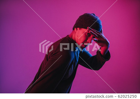 Young Man in a Jumper Dancing Contemporary Dance in Studio. Breakdancing. Dance School Poster. Copy Space. Battle competition announcement. Pink and Blue Background. 62025250