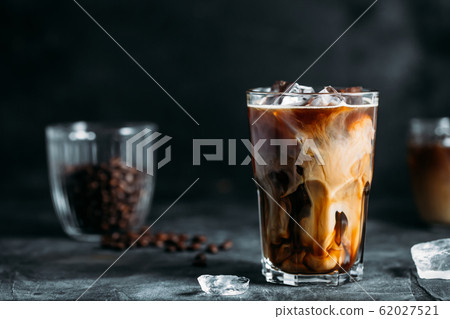 Milk Being Poured Into Iced Coffee on a dark table 62027521