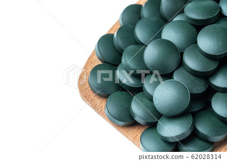 Vitamin and mineral supplements for vegetarians spirulina in tablets in a wooden spoon, close-up. Vitamin and mineral supplements for vegetarians spirulina in tablets in a wooden spoon, close-up. 62028314