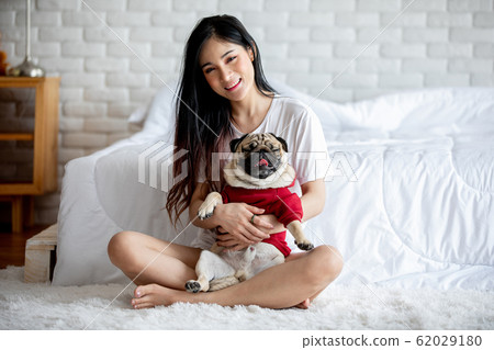 Beautiful Asian young woman playing with her dog and smile with dog pug breed Beautiful Asian young woman playing with her dog and smile with dog pug breed 62029180