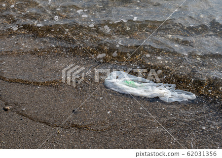 在沙灘海洋垃圾上發射的購物袋 在沙灘海洋垃圾上發射的購物袋 62031356