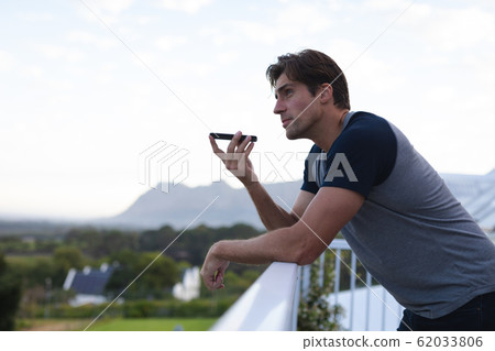 Young man talking on his mobile phone on terrace Young man talking on his mobile phone on terrace 62033806