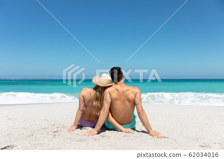 Young couple sitting at the beach 62034016