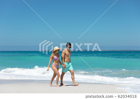 Young couple walking besides the beach 62034018