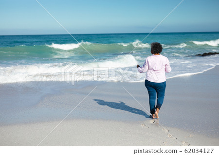 Old woman walking at the beach Old woman walking at the beach 62034127