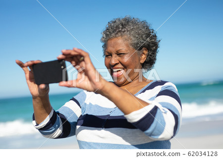 Old woman taking selfies at the beach Old woman taking selfies at the beach 62034128