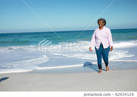 Old woman walking at the beach Old woman walking at the beach 62034129