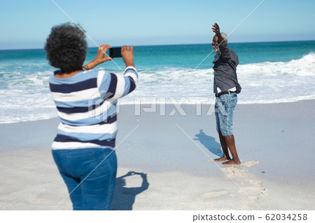 Old couple taking photos at the beach Old couple taking photos at the beach 62034258