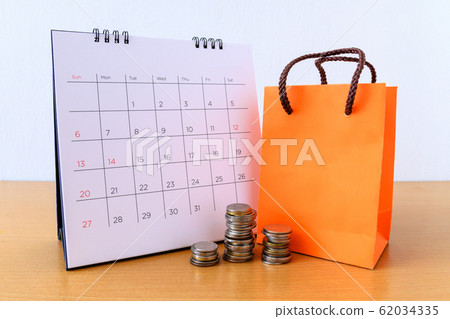 Calendar with days and orange paper bag on wood Calendar with days and orange paper bag on wood 62034335