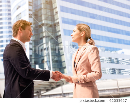 Businessman and businesswoman shaking hands with a smile and happy over building background. Businessman and businesswoman shaking hands with a smile and happy over building background. 62035627