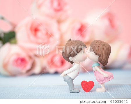 Close up at couple cute dolls in love and kissing together with blurred pink rose background. Use for valentines day, love and relationship concept. Close up at couple cute dolls in love and kissing together with blurred pink rose background. Use for valentines day, love and relationship concept. 62035641