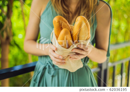 Reusable grocery bags with bread in the hands of a young woman. Zero waste shopping. Zero waste Reusable grocery bags with bread in the hands of a young woman. Zero waste shopping. Zero waste 62036195