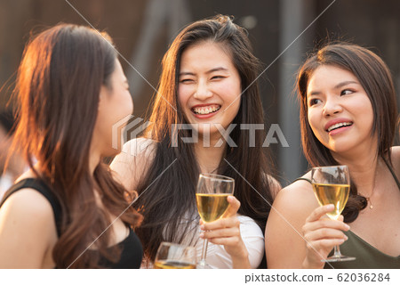 Group of young beautiful happy asian women holding glass of wine chat together with friends Group of young beautiful happy asian women holding glass of wine chat together with friends 62036284