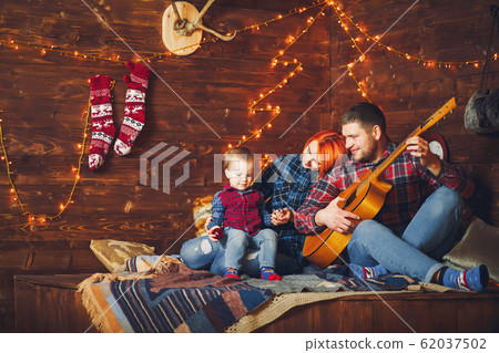 Family sitting at home and father playing on a guitar 62037502