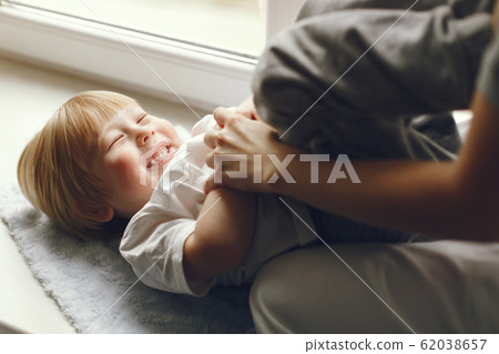 Mother and little son sitting on a windowsill Mother and little son sitting on a windowsill 62038657