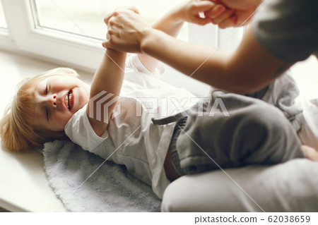 Mother and little son sitting on a windowsill Mother and little son sitting on a windowsill 62038659