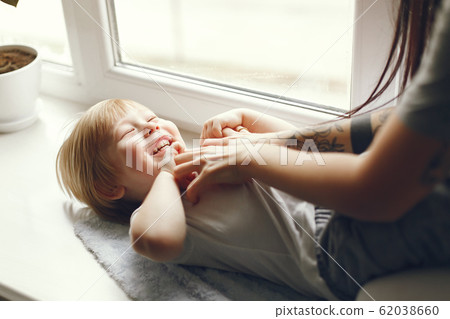 Mother and little son sitting on a windowsill Mother and little son sitting on a windowsill 62038660