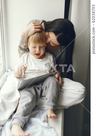 Mother and little son sitting on a windowsill 62038703