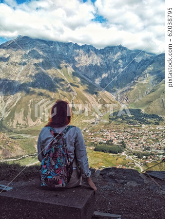 Back girl sitting on the mountain looks at the Back girl sitting on the mountain looks at the 62038795