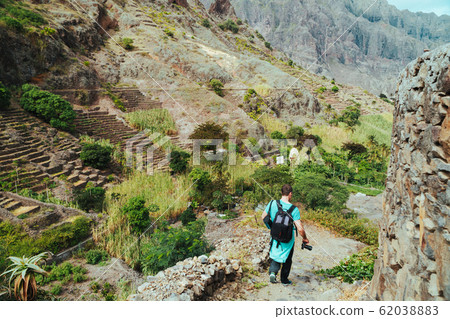 Santo Antao Cape Verde. Hiker with backpack going down the valley. Rocky terrain of high mountain ranges and deep ravines around Santo Antao Cape Verde. Hiker with backpack going down the valley. Rocky terrain of high mountain ranges and deep ravines around 62038883
