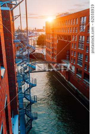 Circular staircase, bridge over canal and red brick buildings in the old warehouse district Speicherstadt in Hamburg in golden hour sunset light, Germany. View from above Circular staircase, bridge over canal and red brick buildings in the old warehouse district Speicherstadt in Hamburg in golden hour sunset light, Germany. View from above 62038919