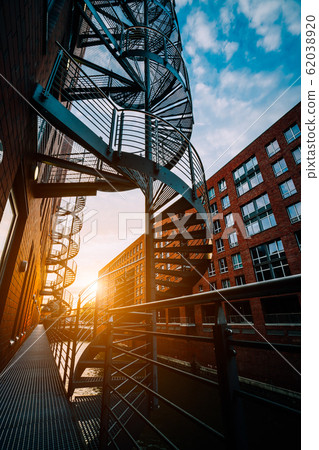 Winding stairs in the old Warehouse District. Narrow canal and red brick buildings of Speicherstadt in Hamburg in the warm sunset light. low angle shot 62038920