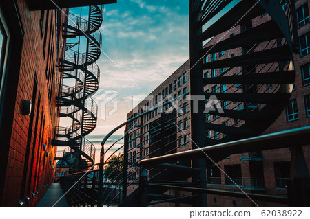 Spiral staircases in the old Warehouse District. Narrow canal and red brick buildings of Speicherstadt in Hamburg. After sunset 62038922
