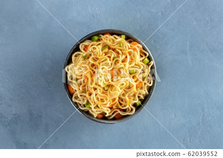 Instant noodles with carrot, scallions, and a sauce, a vegetable soba bowl, shot from above on a slate background Instant noodles with carrot, scallions, and a sauce, a vegetable soba bowl, shot from above on a slate background 62039552