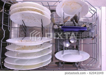 White dirty plates and spoon in dishwasher basket. White dirty plates and spoon in dishwasher basket. 62041049