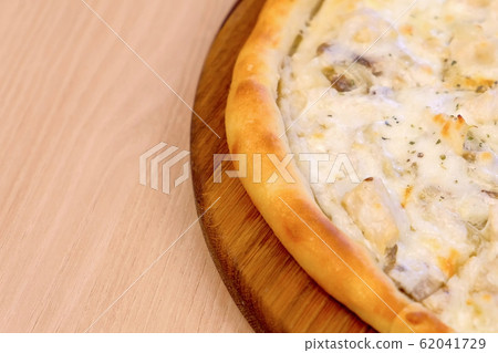 Half of slicing pizza with mushrooms champignons and cheese on wooden board on the table. Close-up side view. 62041729