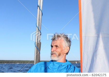 Man sternly looking away amid sail and sky Man sternly looking away amid sail and sky 62042175