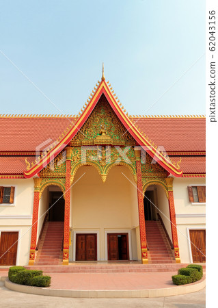 An entrance of Buddhist temple with ornate red roof in Vientiane in Laos against blue sky An entrance of Buddhist temple with ornate red roof in Vientiane in Laos against blue sky 62043156